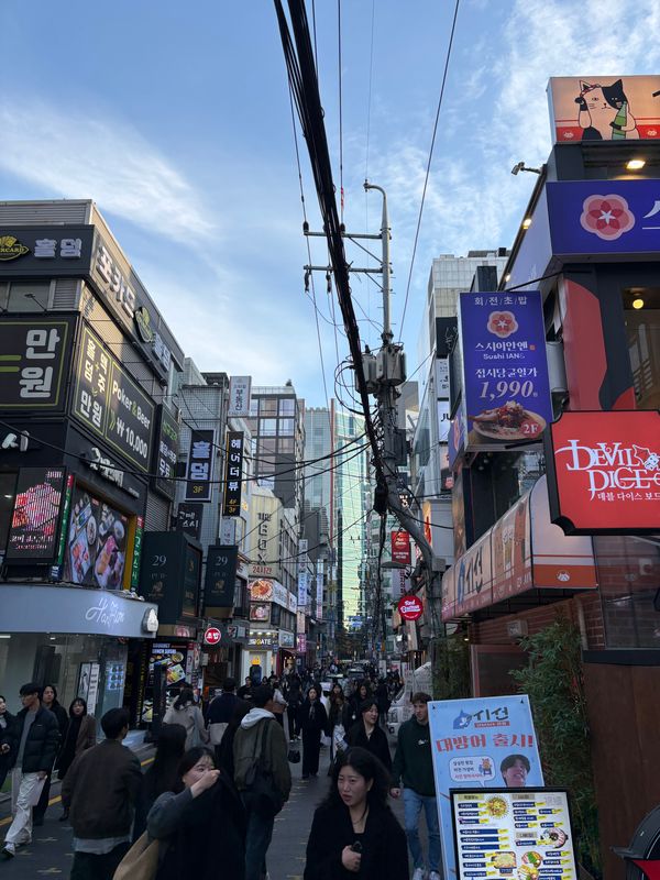 A busy shopping street in Gangnam, Seoul, lined with signs